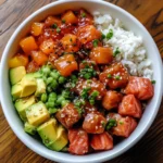 A classic poke bowl served over sushi rice, topped with fresh marinated fish, creamy avocado, sesame seeds, and chopped green onions.